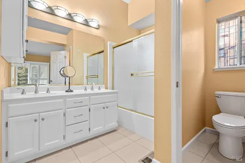 a bathroom with a double vanity sink a toilet and a mirror