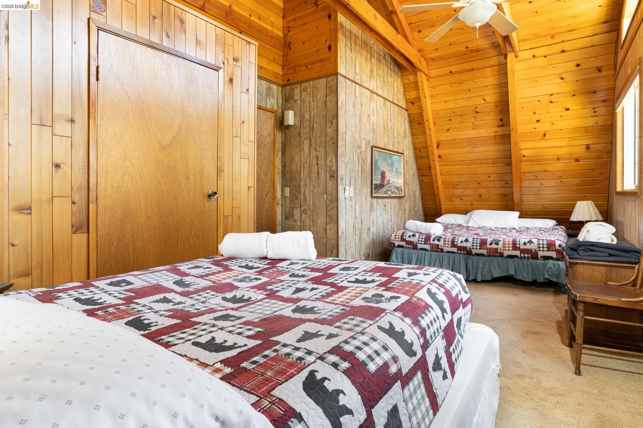 19390 Ferretti Road Groveland, CA 95321 - Photo 27 of 38 Vaulted wood-paneled ceiling with exposed beams, wood-paneled walls, ceiling fan, and built-in door
