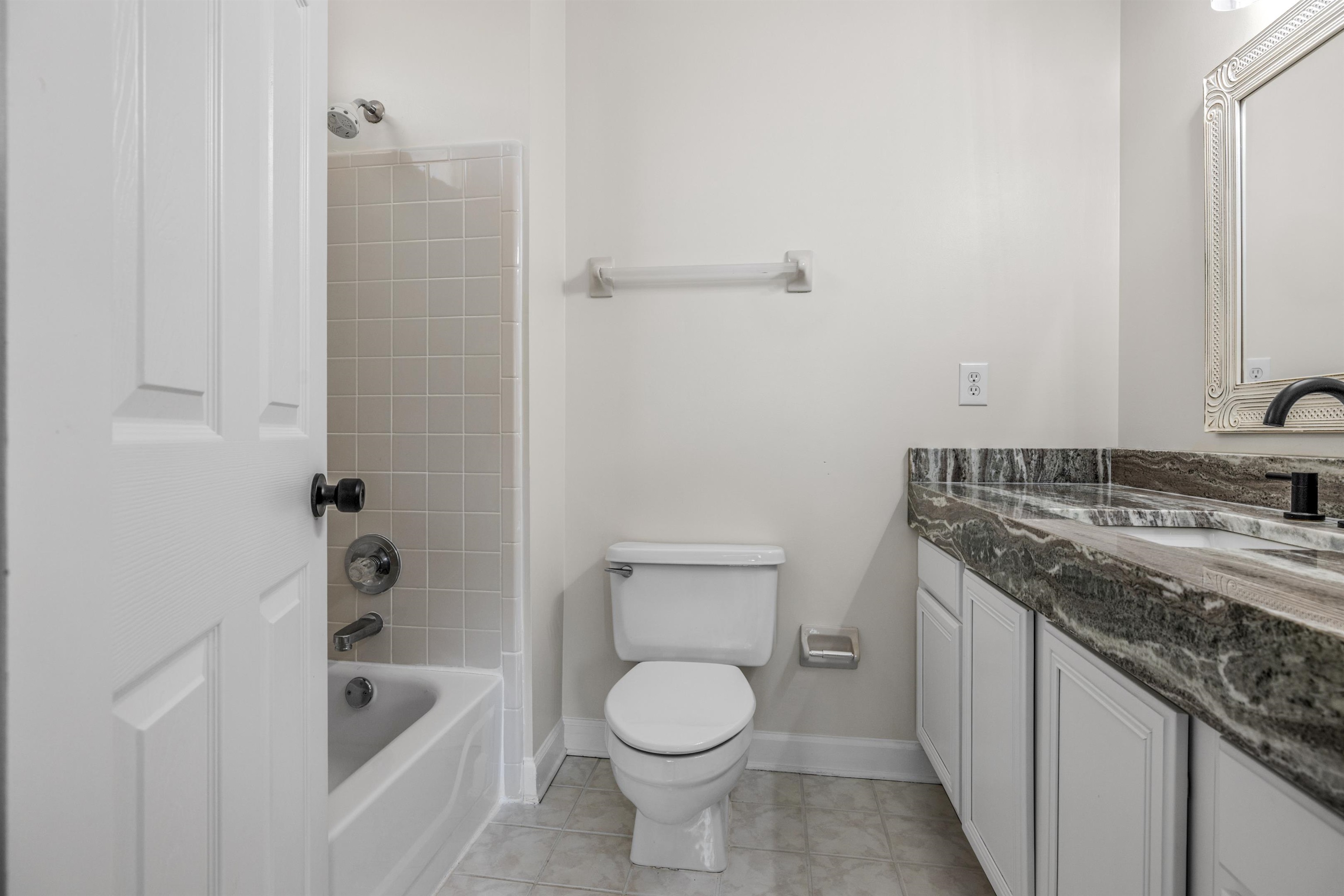 921 Harbor View Drive Memphis, TN 38103 - Photo 8 of 33 Bathroom featuring a tub/shower combination with light-toned wall tiling, white vanity with dual sinks, patterned stone countertop, and matte black fixtures