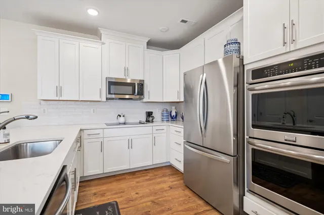 a kitchen with cabinets stainless steel appliances and a sink