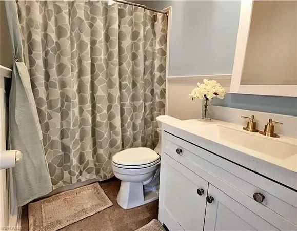 a bathroom with a granite countertop sink and a toilet