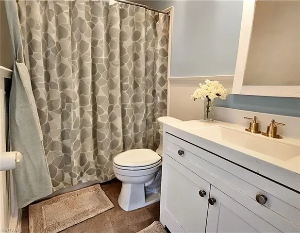 a bathroom with a granite countertop sink and a toilet