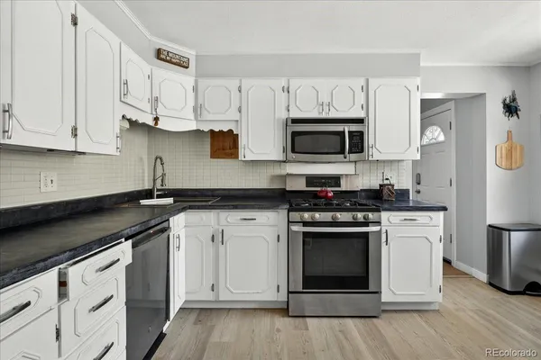 a kitchen with stainless steel appliances granite countertop a stove a sink and a microwave