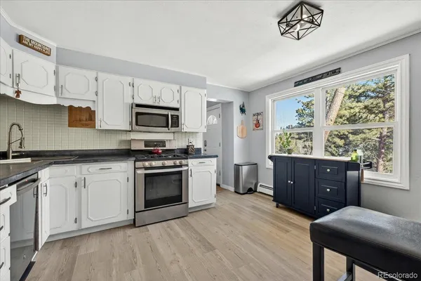 a kitchen with granite countertop a stove a sink dishwasher and a microwave oven with white cabinets