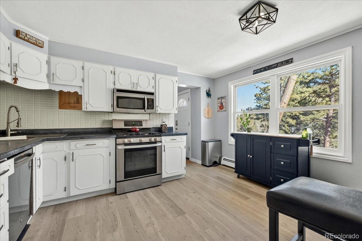 11827 Brook Road Golden, CO 80403 - Photo 10 of 32 a kitchen with granite countertop a stove a sink dishwasher and a microwave oven with white cabinets