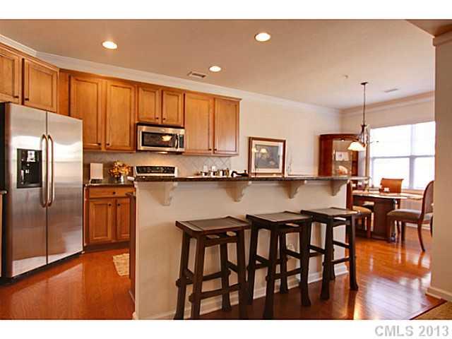 307 Wave Crest Drive, Unit 307 Tega Cay, SC 29708 - Photo 6 of 16 a kitchen with stainless steel appliances granite countertop a refrigerator a stove top oven a sink dishwasher and dining table with wooden floor