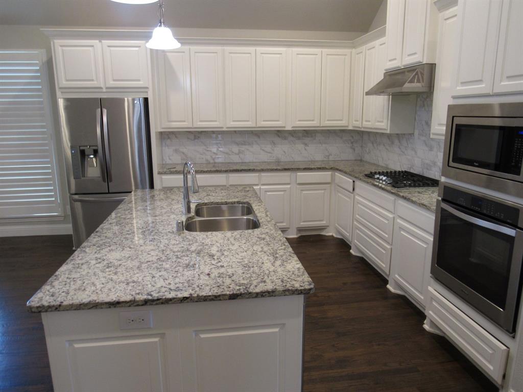 816 Pier Street Little Elm, TX 76227 - Photo 11 of 27 Kitchen featuring white cabinetry, stainless steel appliances, light stone countertops, dark wood finished floors, and pendant lighting