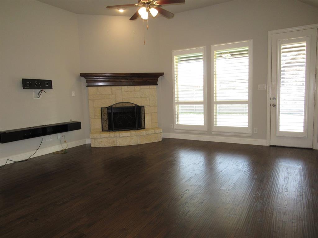 816 Pier Street Little Elm, TX 76227 - Photo 3 of 27 Unfurnished living room featuring dark wood finished floors, a fireplace, and a ceiling fan