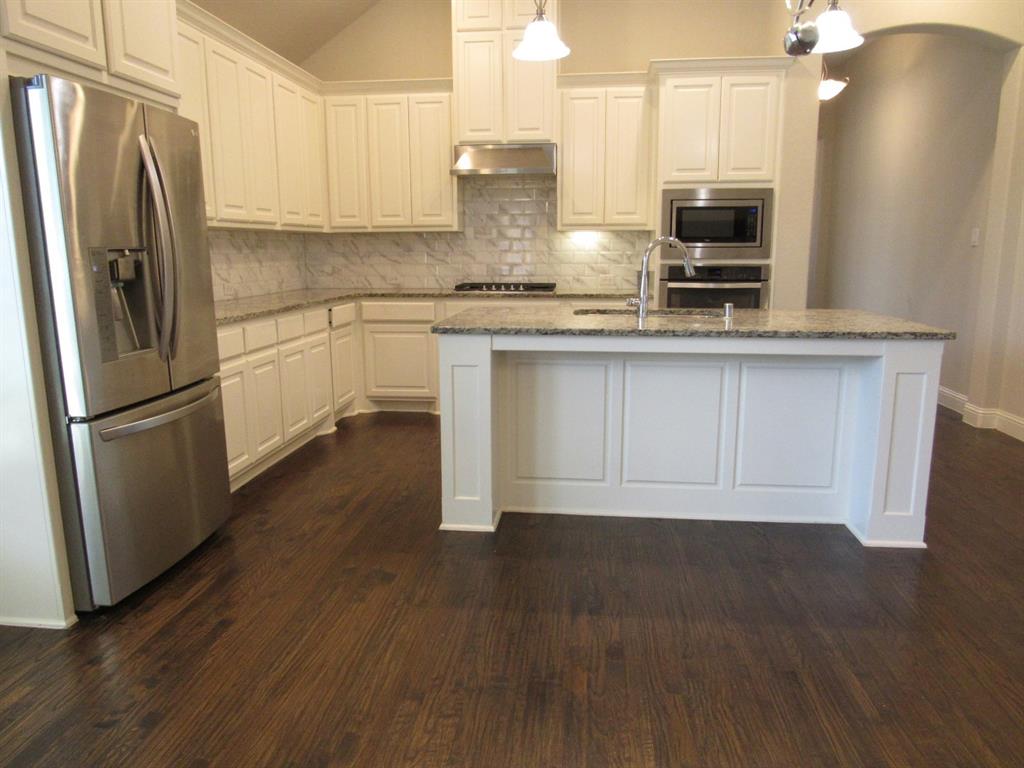 816 Pier Street Little Elm, TX 76227 - Photo 10 of 27 Kitchen with stainless steel appliances, arched walkways, decorative backsplash, lofted ceiling, and white cabinetry