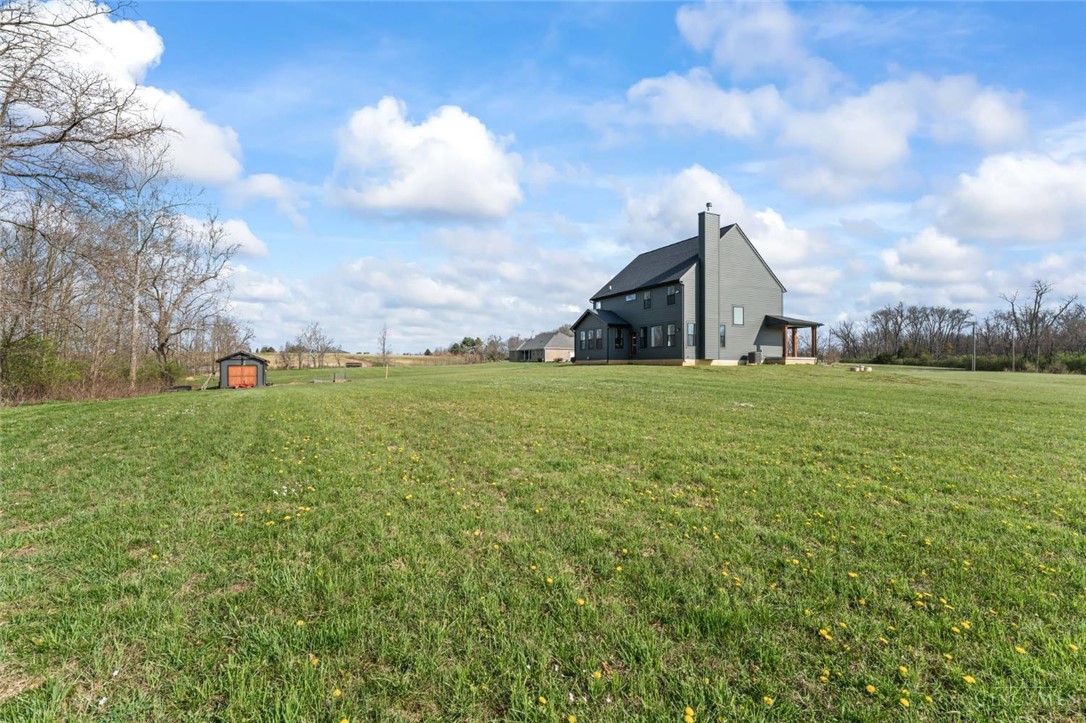 2425 Middleboro Road Clarksville, OH 45113 - Photo 10 of 91 Expansive green yard with a modern home and a practical shed under a dynamic sky.