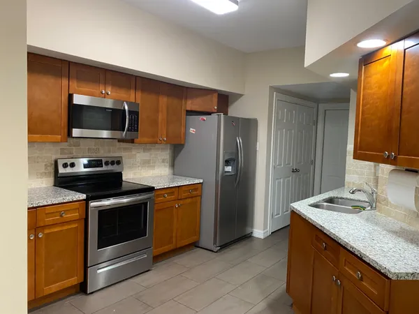 a kitchen with granite countertop wooden cabinets stainless steel appliances and a counter space