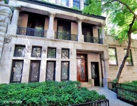 a view of a brick house with large windows and a large tree