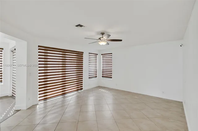 an empty room with windows and ceiling fan