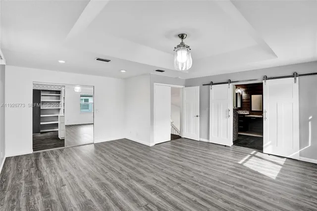 an empty room with wooden floor closet and windows