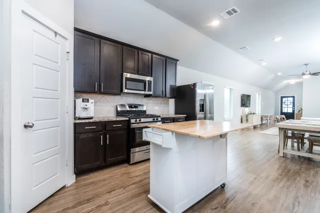 a kitchen with kitchen island granite countertop wooden floors and stainless steel appliances