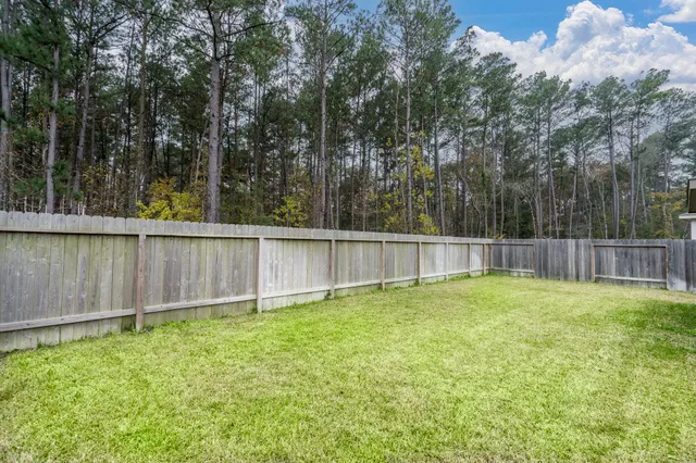 a backyard of a house with lots of green space and wooden fence