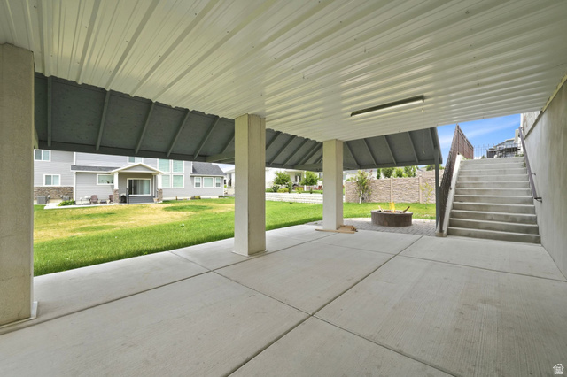 1002 West Temple Rim Lane Payson, UT 84651 - Photo 53 of 68 Covered patio with concrete flooring, supported by square pillars, featuring a metal fire pit and exterior staircase with handrails