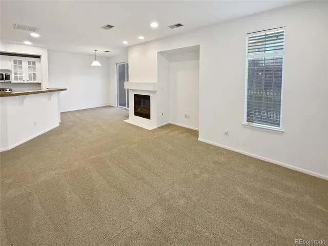 a view of an empty room with a kitchen and a window