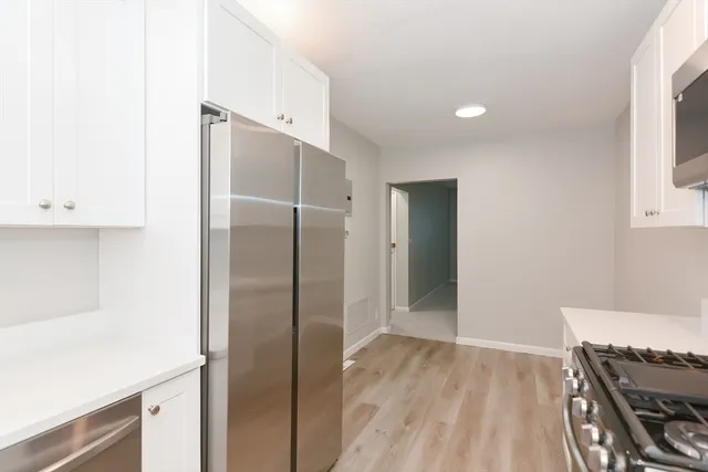 a view of a kitchen with a fridge and wooden floor