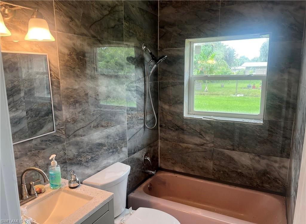 160 Brooks Road North Fort Myers, FL 33917 - Photo 17 of 19 Full bathroom featuring contemporary wall tile, a window, and a built-in bathtub with a shower fixture