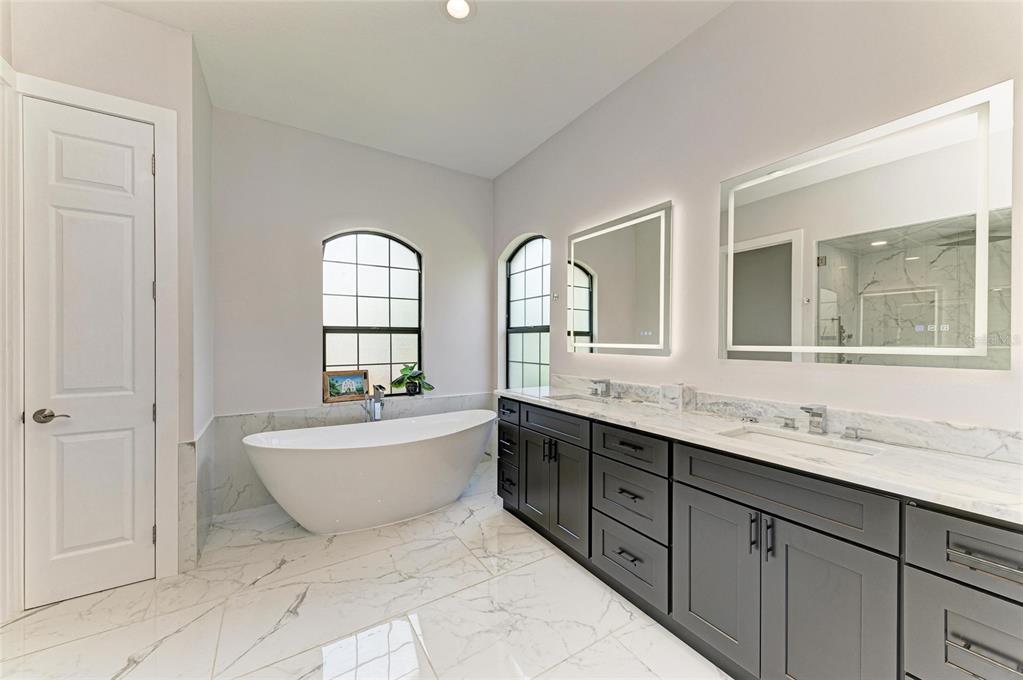 544 Fore Drive Bradenton, FL 34208 - Photo 39 of 95 a spacious bathroom with double vanity a mirror a bathtub and window