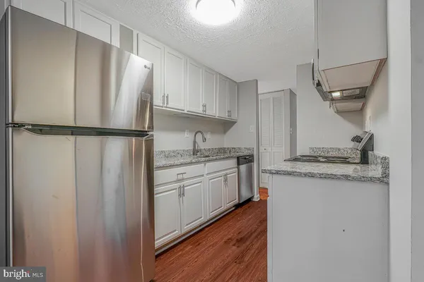 a kitchen with stainless steel appliances granite countertop a refrigerator sink and white cabinets