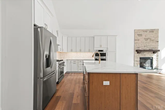 a view of an empty room with wooden floor fireplace and a window