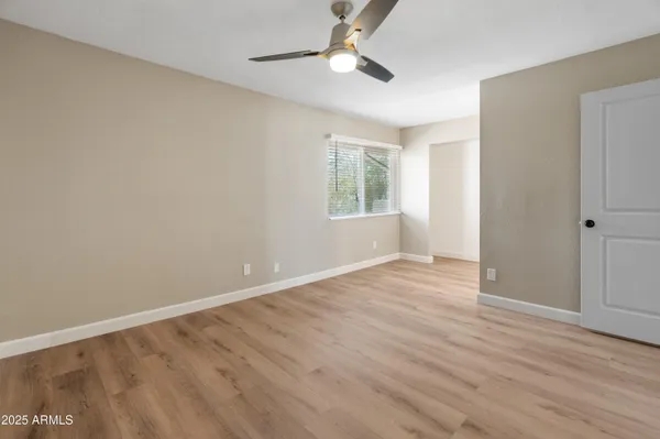 an empty room with wooden floor chandelier fan and windows