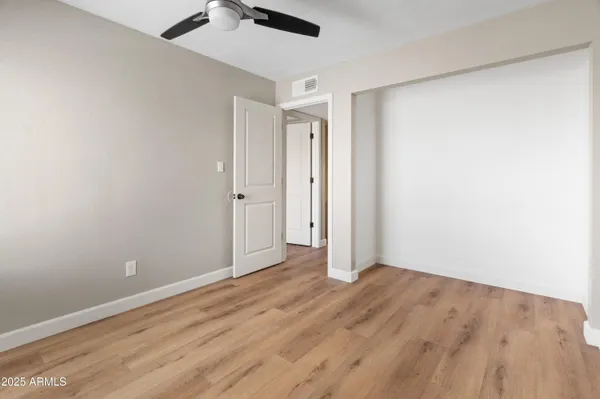 an empty room with wooden floor cabinet and a ceiling fan