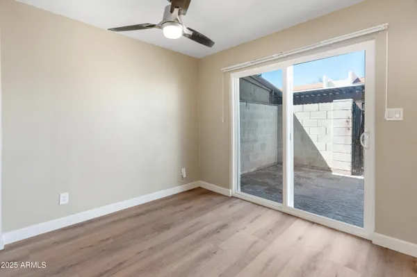 an empty room with wooden floor fan and windows