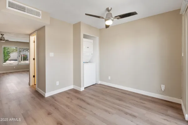an empty room with wooden floor a ceiling fan and windows