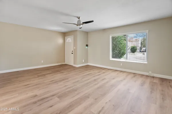 a view of an empty room with wooden floor and a window