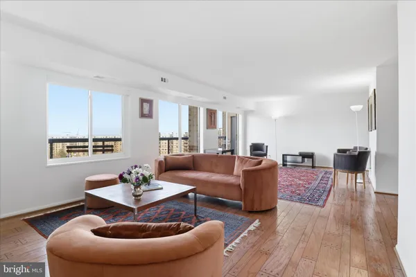 a living room with furniture couches and a dining table with wooden floor