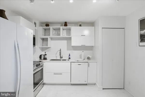 a kitchen with stainless steel appliances a sink a stove a refrigerator and cabinets
