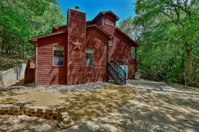 a view of a house with a small yard and large tree