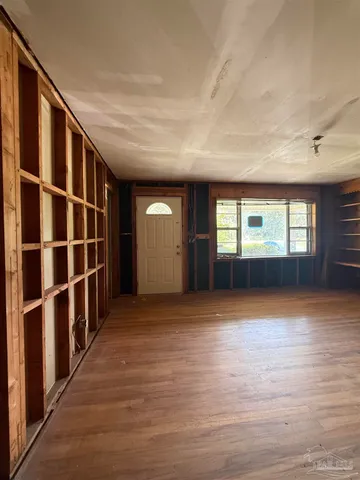 a view of an empty room with window and wooden floor