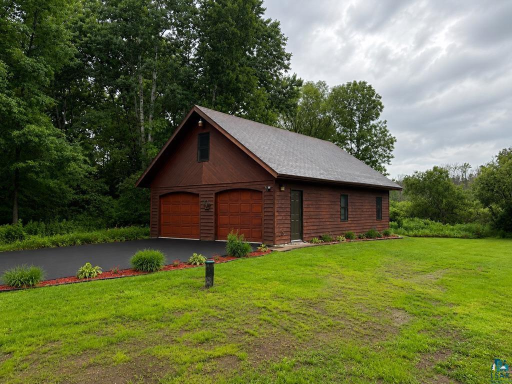 11058 South Brancel Road Solon Springs, WI 54873 - Photo 5 of 6 Two-car detached garage with wood-paneled siding, asphalt shingle roof, and two paneled garage doors