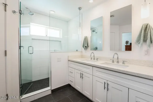 a bathroom with a double vanity sink mirror and shower