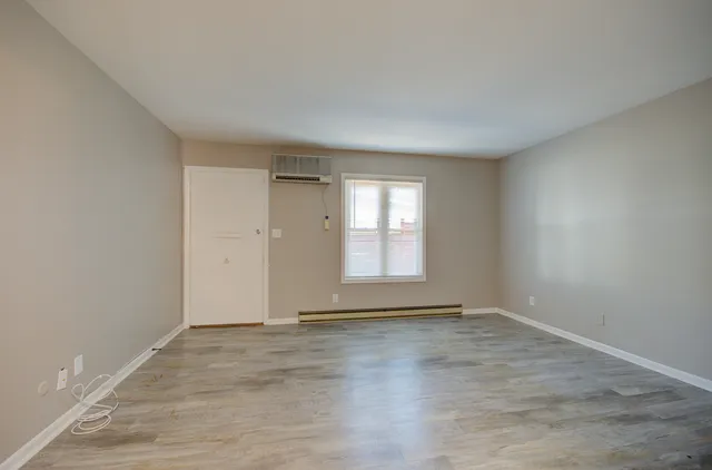 a view of an empty room with wooden floor and window