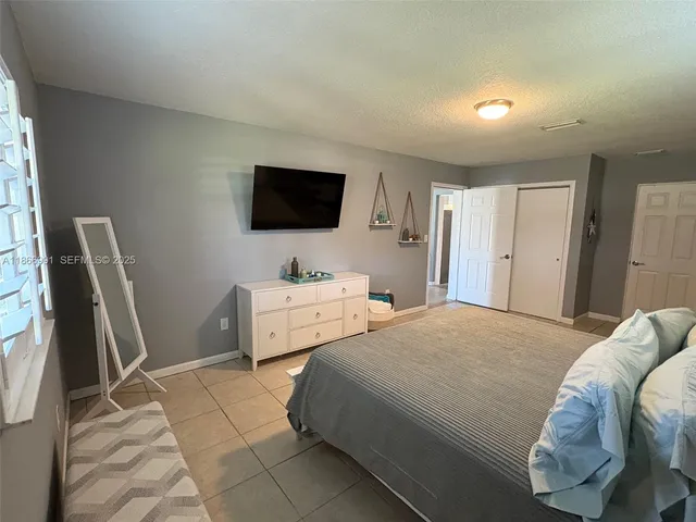 a bedroom with a bed and a potted plant on dresser