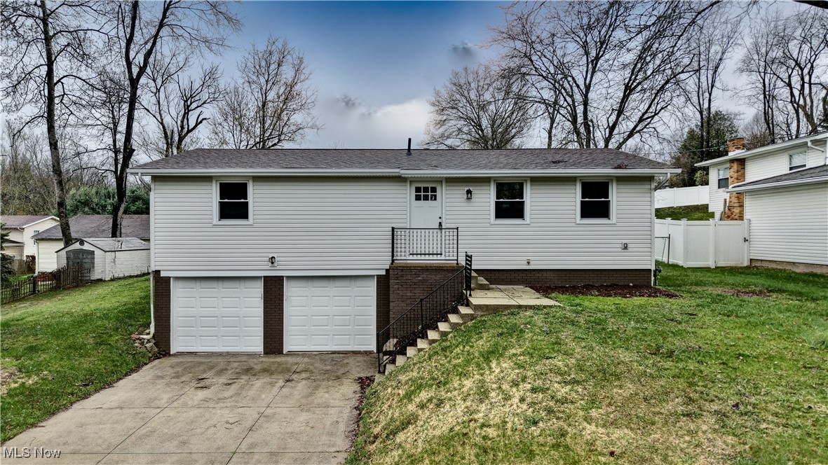 494 Moore Road Akron, OH 44319 - Photo 1 of 30 Rear view of house featuring an attached garage, driveway, fence, and a lawn
