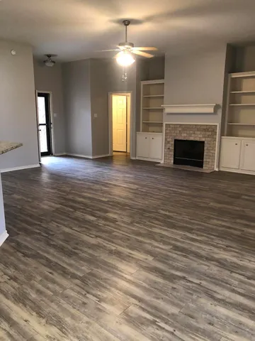 an empty room with wooden floor fireplace and windows