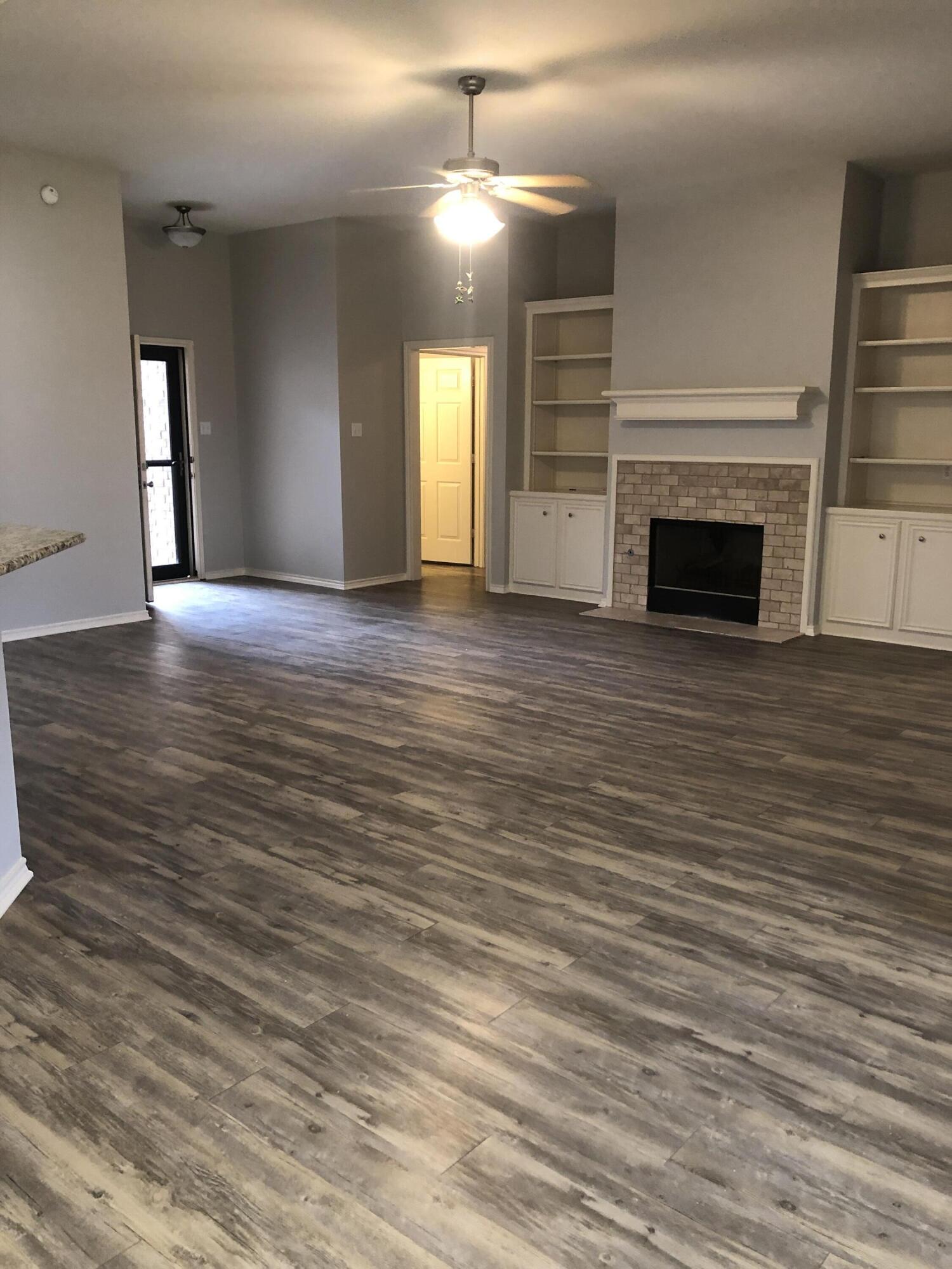 7528 84th Street Lubbock, TX 79424 - Photo 3 of 20 an empty room with wooden floor fireplace and windows