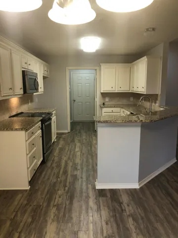 a kitchen with stainless steel appliances granite countertop a stove a sink and a microwave