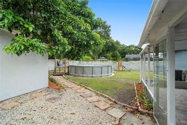 a view of a backyard with plants and large tree