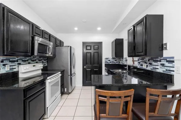 a kitchen with stainless steel appliances kitchen island granite countertop a stove refrigerator and microwave