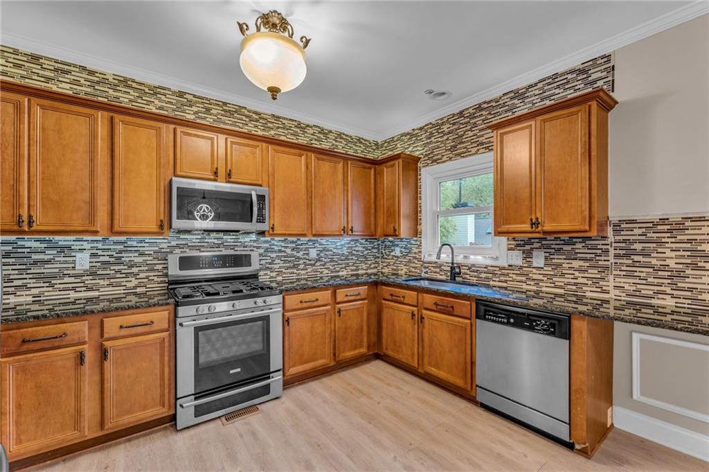 1093 3rd Street Stone Mountain, GA 30083 - Photo 8 of 43 a kitchen with stainless steel appliances granite countertop a sink a stove top oven and cabinetry