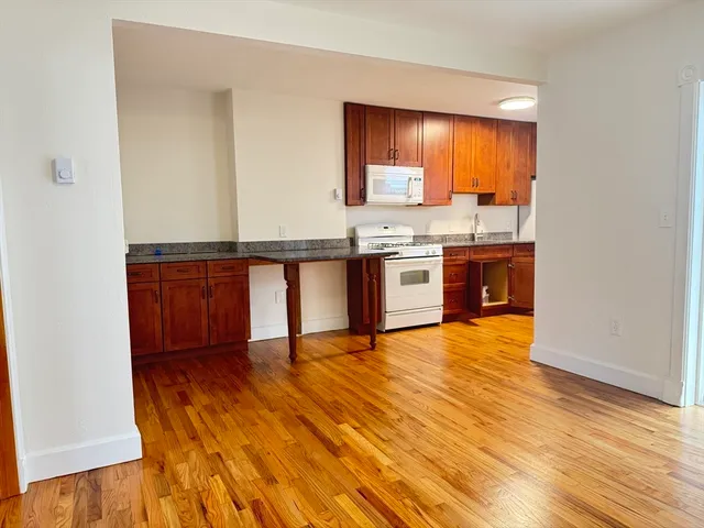 a view of kitchen with stainless steel appliances granite countertop a stove and a wooden floors