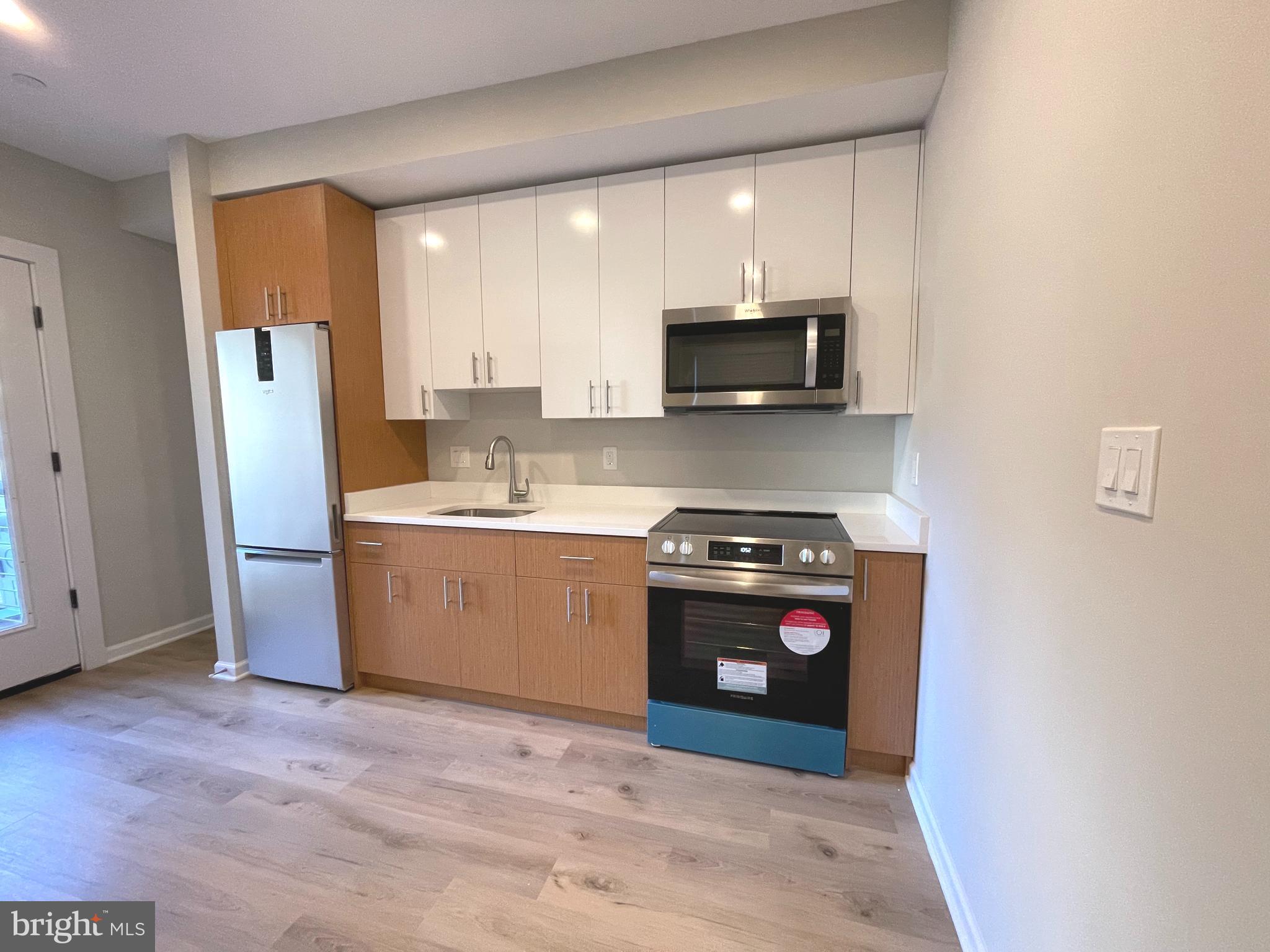 1307 K Street Southeast, Unit 101 Washington, DC 20003 - Photo 3 of 8 a kitchen with stainless steel appliances a stove a microwave a sink a refrigerator and cabinets