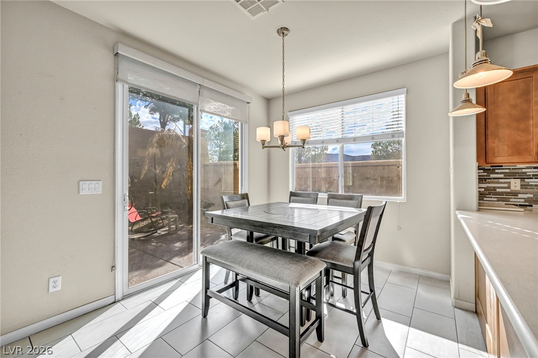 389 Fringe Ruff Drive Las Vegas, NV 89148 - Photo 4 of 53 Natural light pours across the tiled dining area through large windows and sliding glass doors.